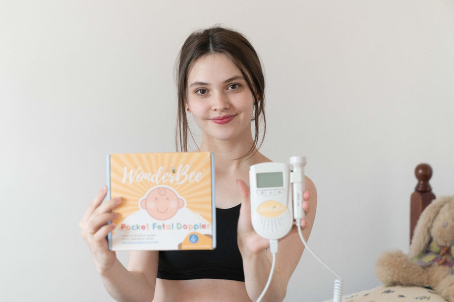 Expectant parent holding the WonderBee Classic Pocket Fetal Doppler and its branded box