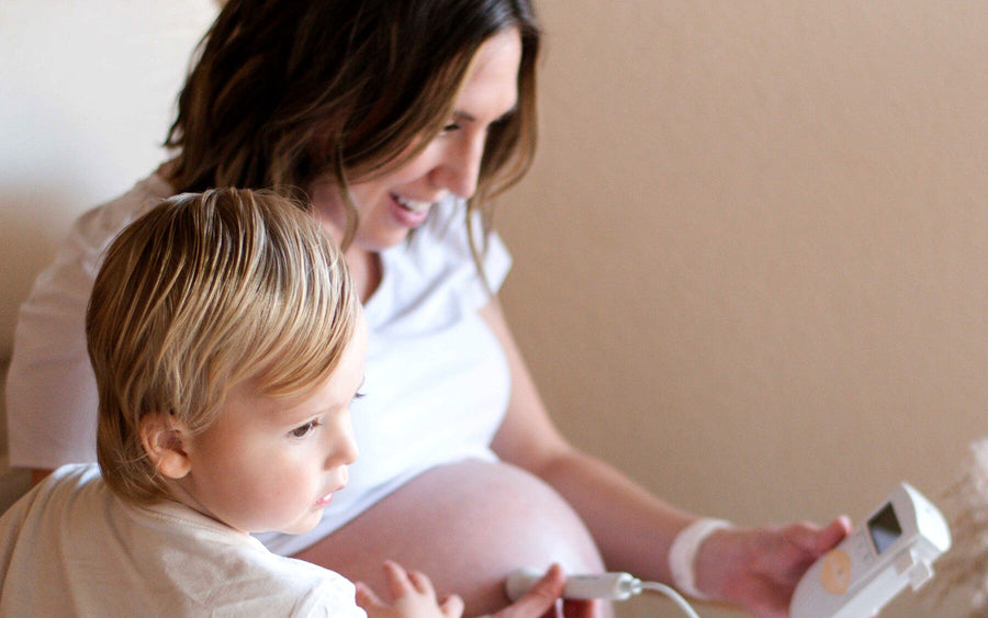 Expectant parent and young child sharing a family bonding moment with the WonderBee Classic Pocket Fetal Doppler